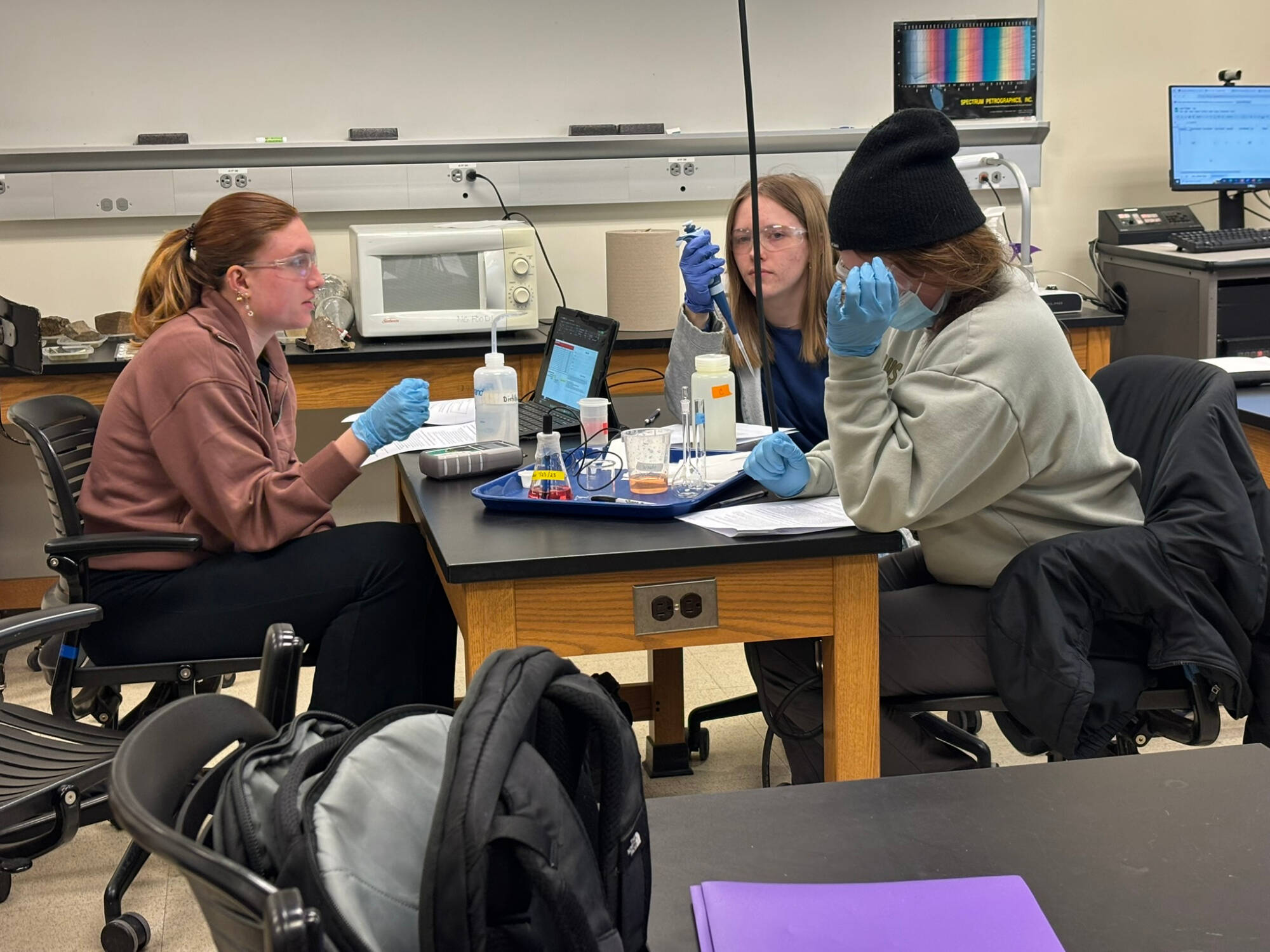 students sitting around a lab table wearing lab gear